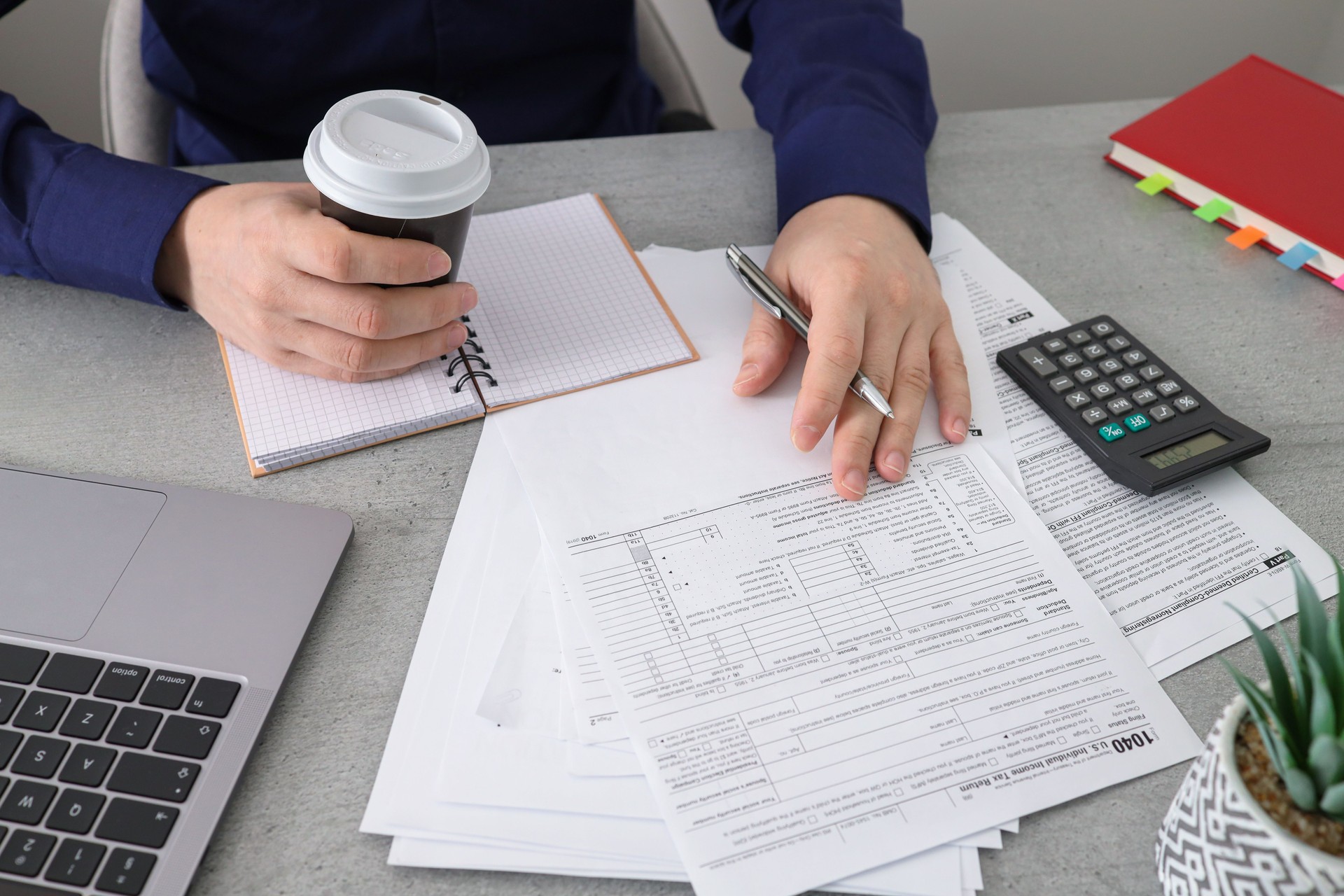 Businessman filling 1040 tax form with help laptop caluclator and note at office desk.